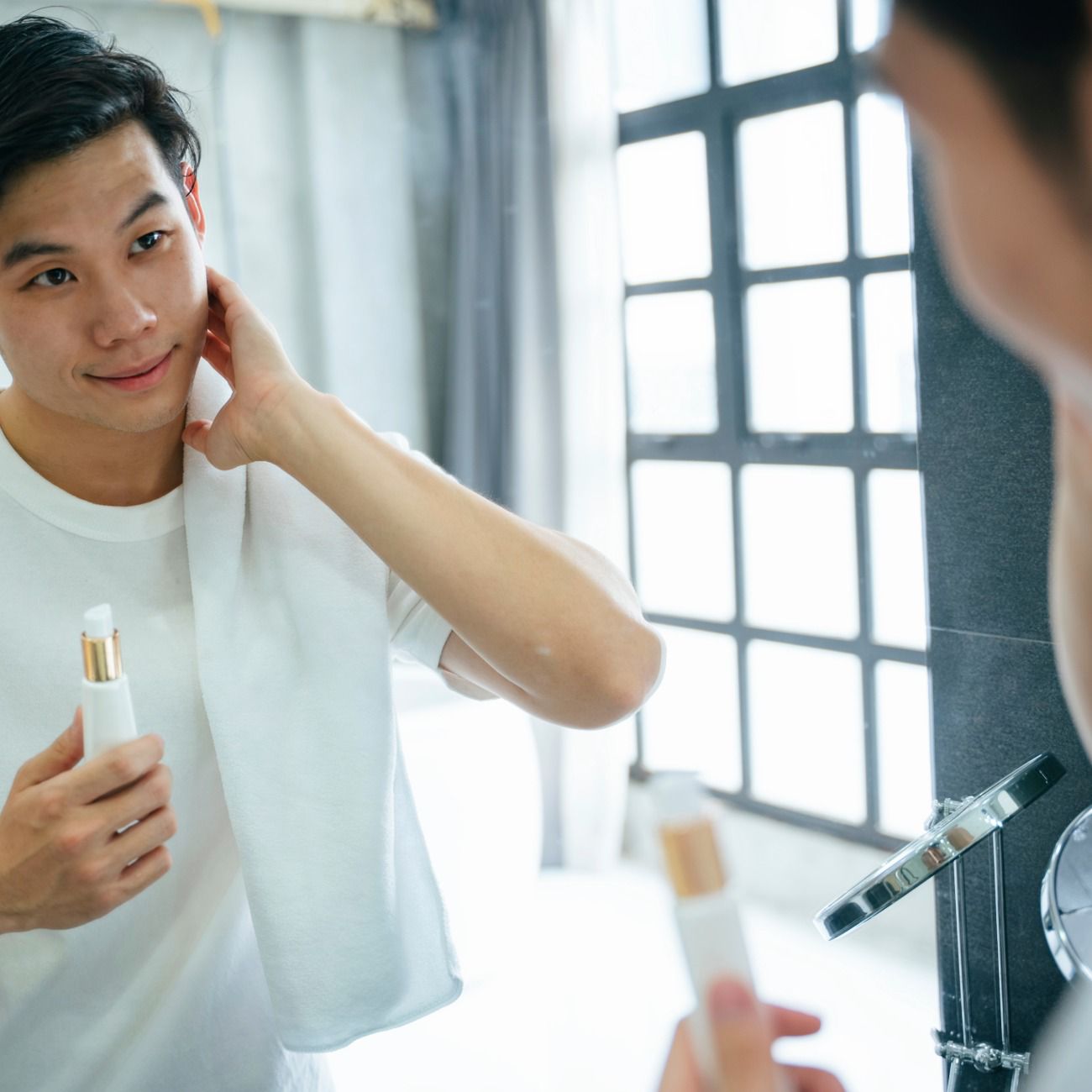 Man applying skin care moisturiser in the bathroom